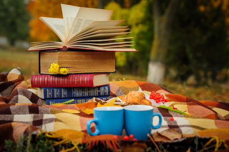 Romantic autumn still life with books, plaid, croissant, coffee cups and leavesの写真素材