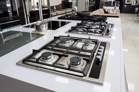 Rows of gas stoves with stainless tray selling in appliance retail store