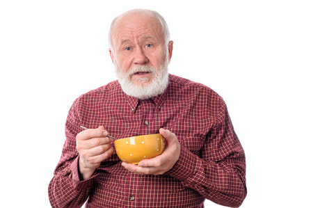 Senior man eating from oragne bowl , isolated on whiteの写真素材
