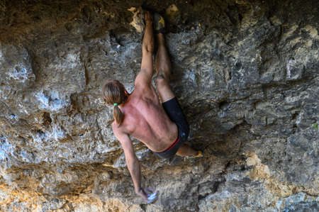 Young male climber bouldering a rock wall in a caveの写真素材
