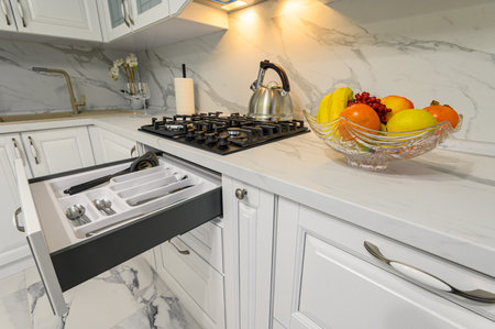 Open drawers with kitchenware at modern white kitchenの写真素材