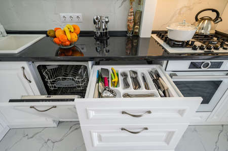 Luxurious white modern kitchen interior, drawers pulled out, dishwashers door openの写真素材