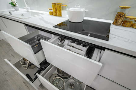 Luxurious white and black modern kitchen interior, drawers pulled out