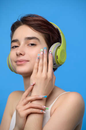 Cute young brunette listening to music using wireless headphones