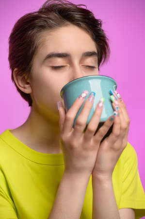 Bored young girl drinking from big cup of tea or coffee at morningの写真素材