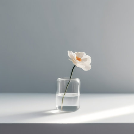 A single white flower in a glass of water. AI generative image.の素材
