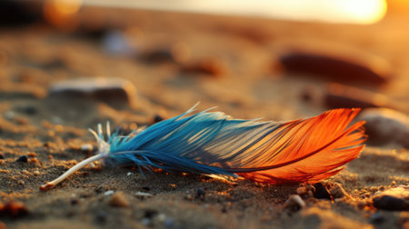 A blue and orange feather laying on top of a sandy beach. Generative AI image.の素材