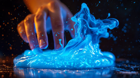 A persons hand is touching a liquid that has blue lights, AIの素材