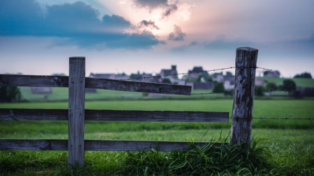 A fence with barbed wire and a green field in the background, AIの素材