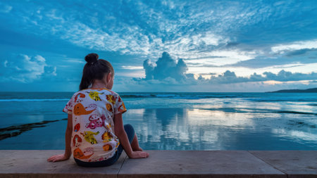 A young girl sitting on a ledge looking out at the ocean, AIの素材