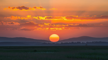 A sunset over a field with mountains in the background, AIの素材