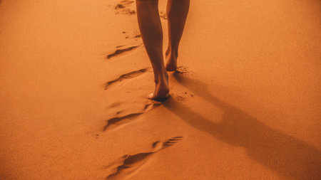 A person walking in the sand with their feet leaving footprints, AIの素材