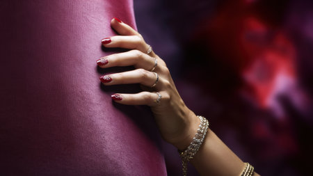 A womans hand with red nails and gold jewelry on a purple cloth, AIの素材