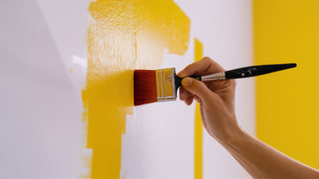 A person painting a wall with yellow paint and holding the brush, AIの素材