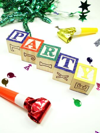 child's blocks spelling party with confetti, noise makers, and ribbon isolated on whiteの写真素材