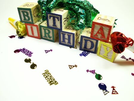 Childs blocks spelling birthday isolated on white. Blocks surrounded by ribbon, noise makers and confetti.の写真素材
