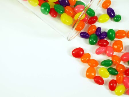 Jelly beans falling out of a glass jar shot from above isolated on white.