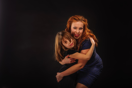 Young girl and mature mother embracing on black backgroundの写真素材