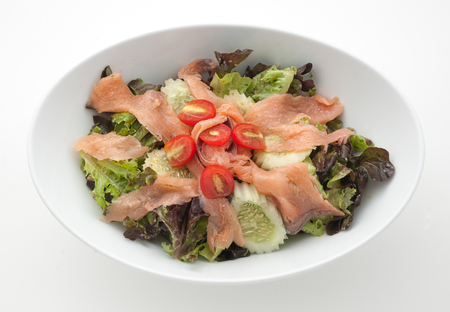 Slised smoked salmon with salad leaves isolated on whiteの写真素材
