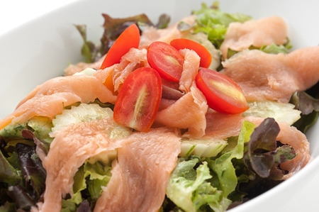 Slised smoked salmon with salad leaves isolated on whiteの写真素材