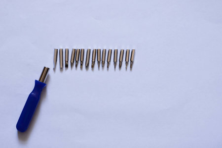 blue screwdriver with a metal head and a set of metal nozzles on a white backgroundの写真素材
