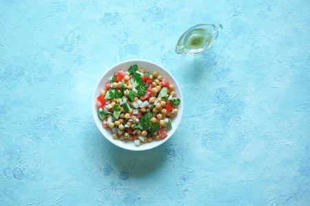 Summer vegetarian diet. Salad with chickpeas and vegetables in a bowl on a blue backgroundの写真素材
