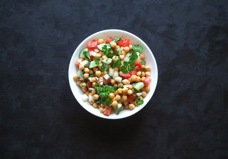 Chickpea salad with vegetables on a black background. Summer vegetarian dietの写真素材