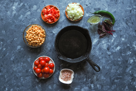 Old pan and a set of vegetables with chickpeas for frying. Top view
