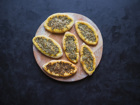 Scones with zatar. Manakish Arabic on a wooden chopping board on a black tableの写真素材