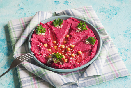 A plate with beetroot hummus on a blue tableの写真素材