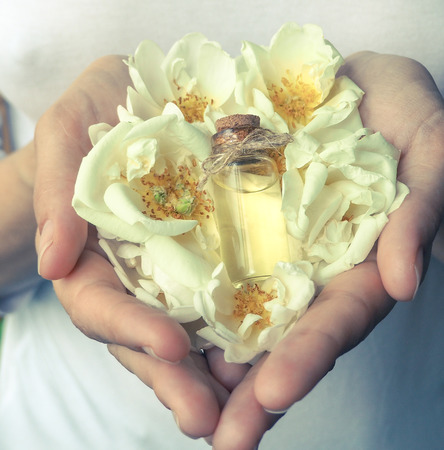 Scented rose oil in the palms. Floral scents in a mini bottleの写真素材
