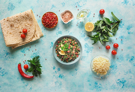 Traditional tabbouleh salad with ingredients to it on the kitchen tableの写真素材