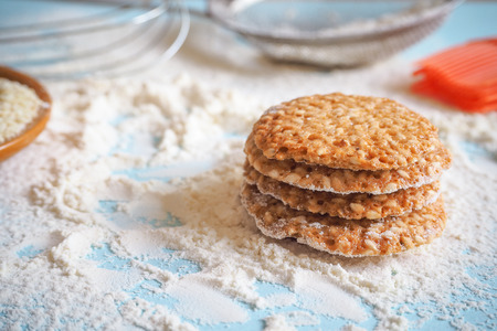 Top view of product set for cooking cookies, kitchenware and several round cookies with sesame on a...