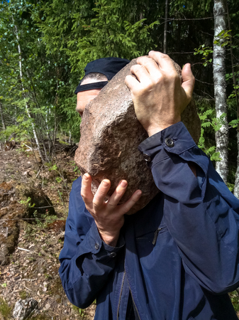 A worker carrying a big heavy rockの写真素材