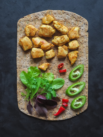 Pieces of fried chicken curry fillet on rye flatbread with vegetablesの写真素材