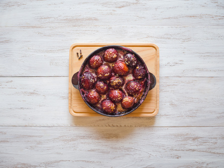 Dessert of baked plum in a pan with cloves, cinnamon, honey and zestの写真素材