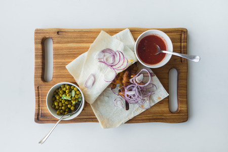 Kebab with peas, onions and red sauce in pita bread on a portion board. Top viewの写真素材