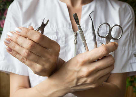 The manicurist is holding a tool. Close up.