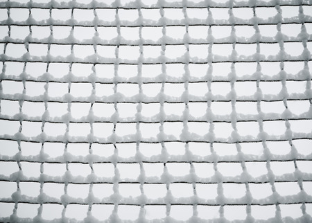 Mesh netting covered with snow. Winter industrial background.