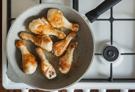 Fried chicken legs are fried in a pan on a gas stove.の写真素材