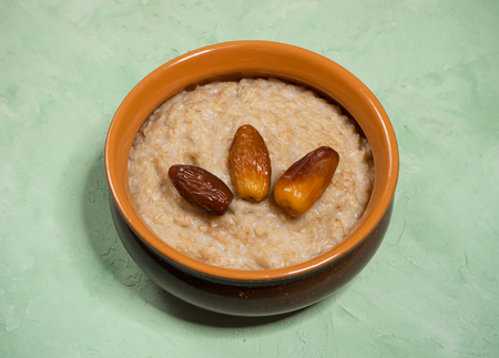 Healthy food. Oatmeal with dates on the green table.の写真素材