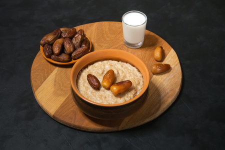 Healthy food. Oatmeal with dates with milk on the black table.の写真素材
