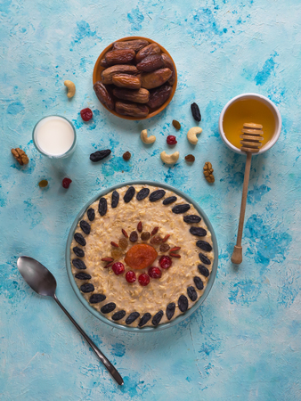 Oatmeal porridge with dried fruits on a blue table. Top view.の写真素材