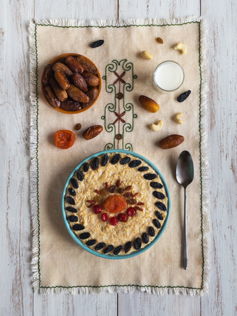 Oatmeal porridge with dried fruits on a wood table. Top view.の写真素材