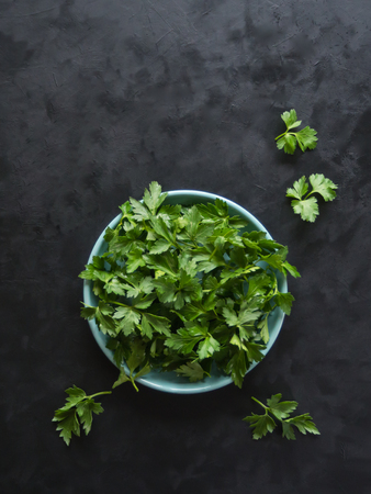 Parsley leaves flat lay. Fresh parsley on a plate on a black table. Top view.の写真素材