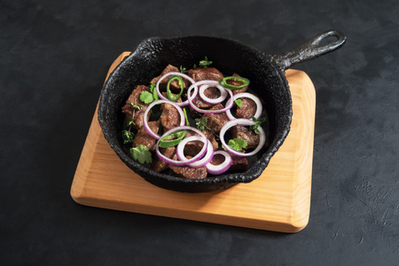 Pieces of roast beef in an old black panの写真素材