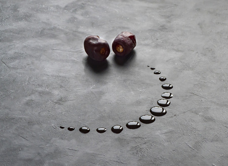 Black Ramadan background with dates and dates syrup poured in the shape of crescent moon.の写真素材
