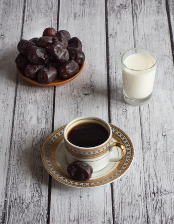 Coffee with dates and a glass of milk on a white wooden table.の写真素材