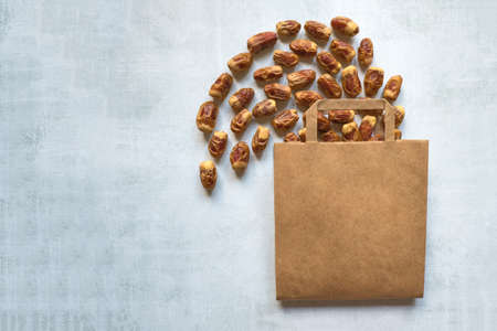 Different varieties of dates fruits are laid out on a wooden table with a bag.