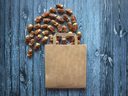 Different varieties of dates fruits are laid out on a wooden table with a bag.の写真素材